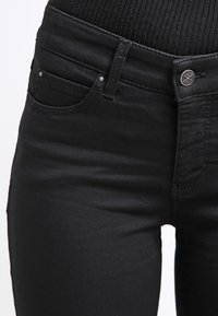 Svart denimjeans med slim fit, med fem lommer, frontknapp og subtil søm. Glatt tekstur og minimal maskinvare.