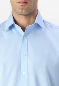 Világoskék gombos ing, selymes fényű, galléros kialakítással, fehér gombokkal, sima tapintással, karcsú fazonnal és normál mandzsettákkal.