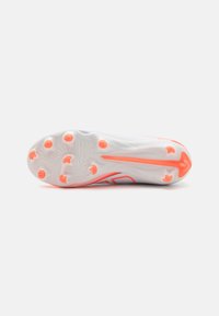 Botas de fútbol blancas con un upper texturizado y acentos en naranja. Presentan una suela con un patrón y tacos prominentes para una mejor tracción.