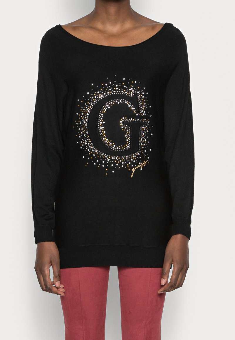 Schwarzer, langärmeliger Pullover mit einem großen, verzierten "G"-Design in Silber- und Goldakzenten. Stricktextur, lockerer Sitz und runder Halsausschnitt.