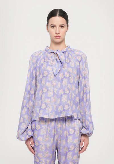 Lilac floral-patterned blouse with a tied neckline, long billowing sleeves, and a relaxed fit, made from lightweight, textured fabric.