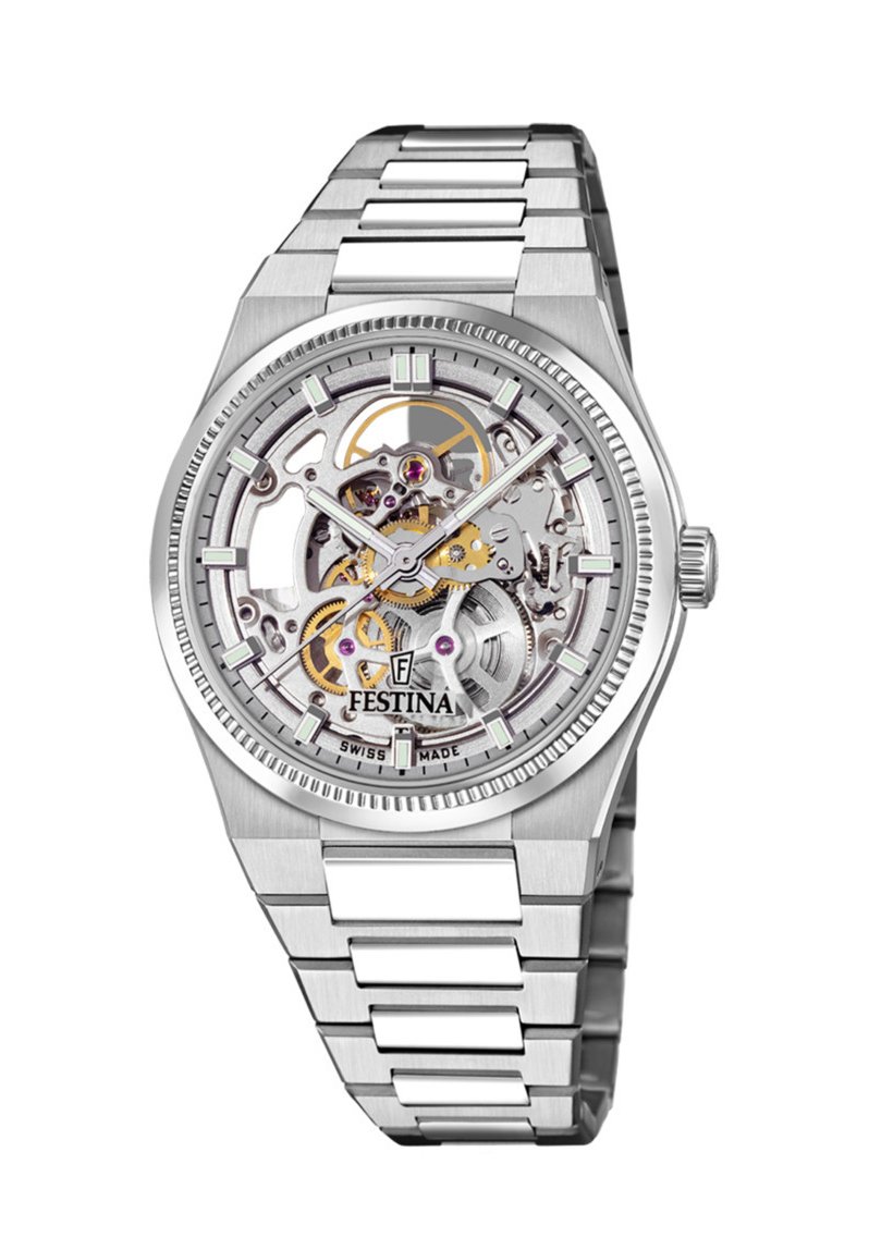 Reloj de acero inoxidable plateado con una esfera esqueletizada transparente que muestra engranajes dorados y joyas moradas, con marcadores horarias luminosos.