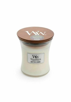 Barattolo di candela in vetro a forma curva, cera bianca, coperchio in legno marrone e un'etichetta con la scritta "WoodWick White Tea & Jasmine."