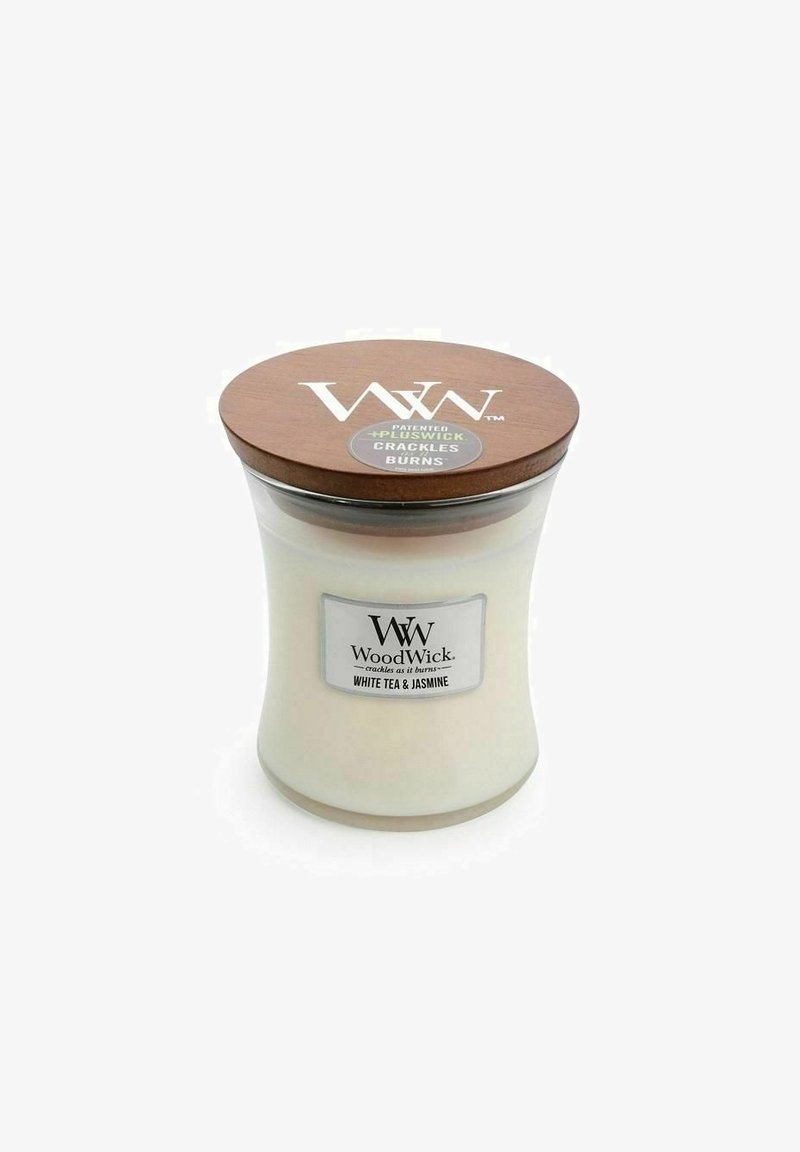 Lasikynttilä purkki, jossa on kaareva muoto, valkoinen vahaliuska, ruskea puukansi ja etiketti, jossa lukee "WoodWick Valkoinen Tee & Jasmiini."