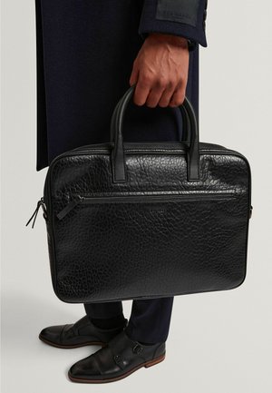 Valigetta nera in pelle con finitura testurizzata, doppio manico superiore e tasca frontale con cerniera. Caratterizzata da bordi arrotondati e marchio discreto.