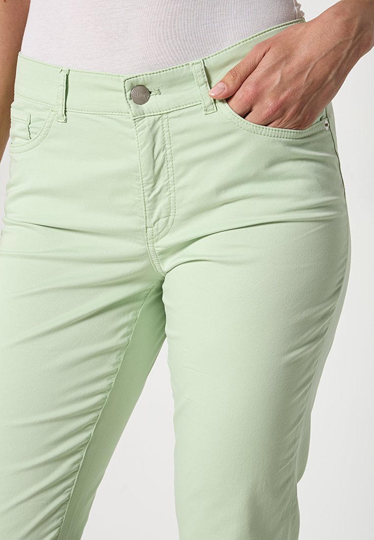 Hellgrüne Hosen aus glattem, dehnbarem Stoff, mit einem klassischen Fünf-Taschen-Design und silberner Metallknopf-Details.