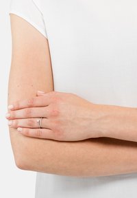 Anelli d'argento su una mano con tono di pelle chiaro; uno presenta un piccolo accento a forma di stella e l'altro ha una fila di piccole pietre incastonate.