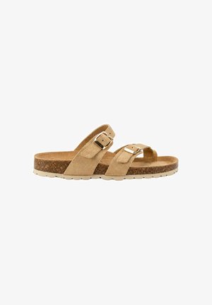 Sandalia de ante beige con dos tiras ajustables con hebilla y plantilla de corcho sobre una suela blanca texturizada.