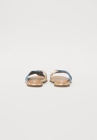 Flate sandaler med en gullmetallramme, blå stropper og en brun teksturert fotseng. Minimalistisk design, åpen tå-stil, ingen utsmykninger.