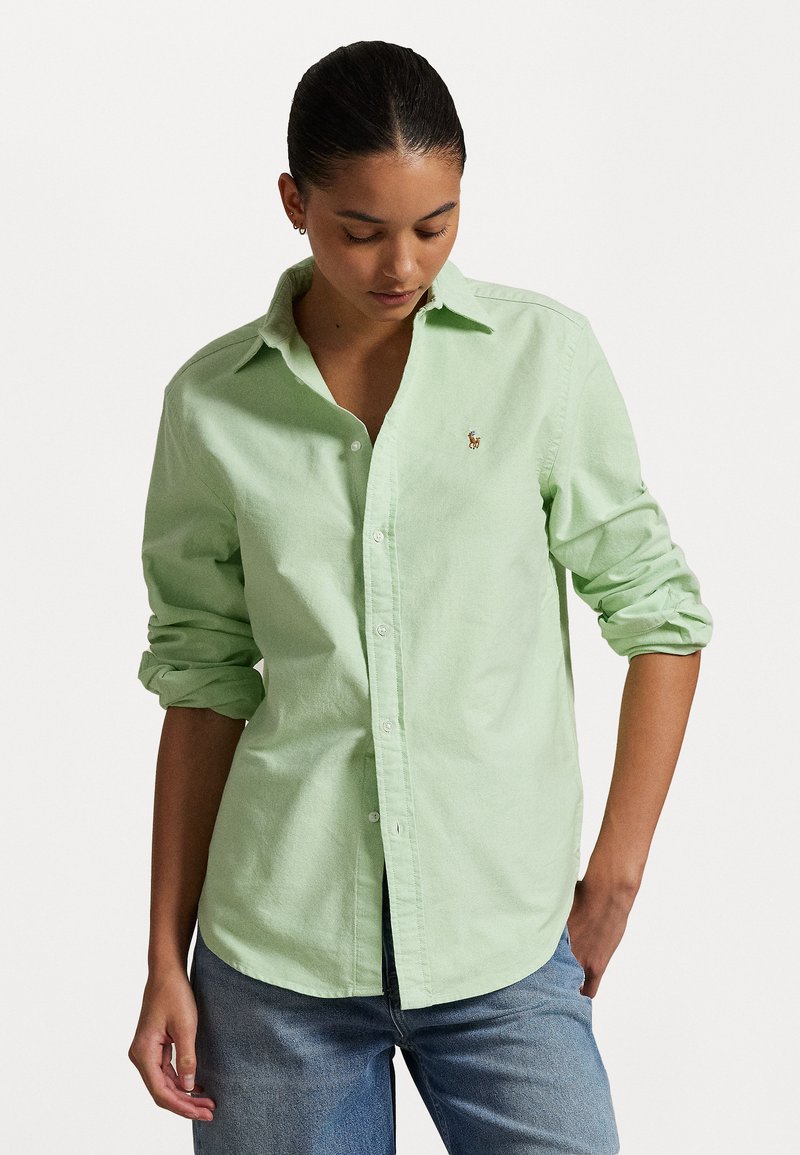 Chemise boutonnière vert clair en tissu doux, dotée d'un col classique et de manches retroussées. Petit logo brodé sur la poitrine gauche.