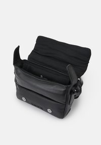 Borsa a tracolla in pelle nera con flap aperto, mostrando l'interno foderato in tessuto e le chiusure a bottone magnetico sul davanti.