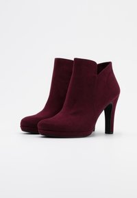 Burgundy suede ankle boots with a smooth texture, rounded toe, and a platform design. Features a high heel and side cutout.