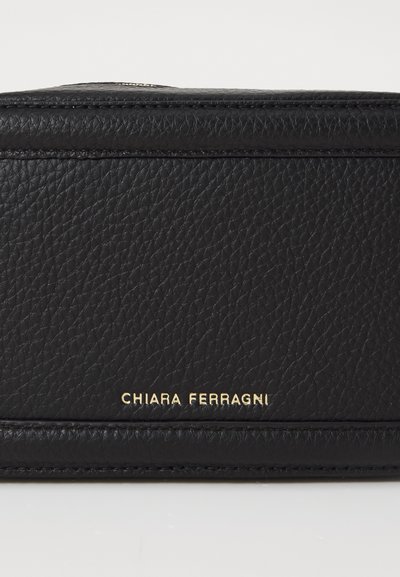 Portafoglio in pelle nera con finitura testurizzata. Presenta il nome del marchio in oro stampato "CHIARA FERRAGNI" sul davanti. Design compatto e rettangolare.
