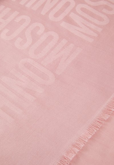 Tissu rose avec une texture tissée et douce, présentant des lettres en relief bien visibles. Les bords sont effilochés, créant une finition décontractée.
