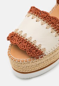 Sandale plateforme avec tige en cuir beige, détails en crochet couleur rouille, semelle intermédiaire en jute tressé et semelle extérieure en caoutchouc blanc.