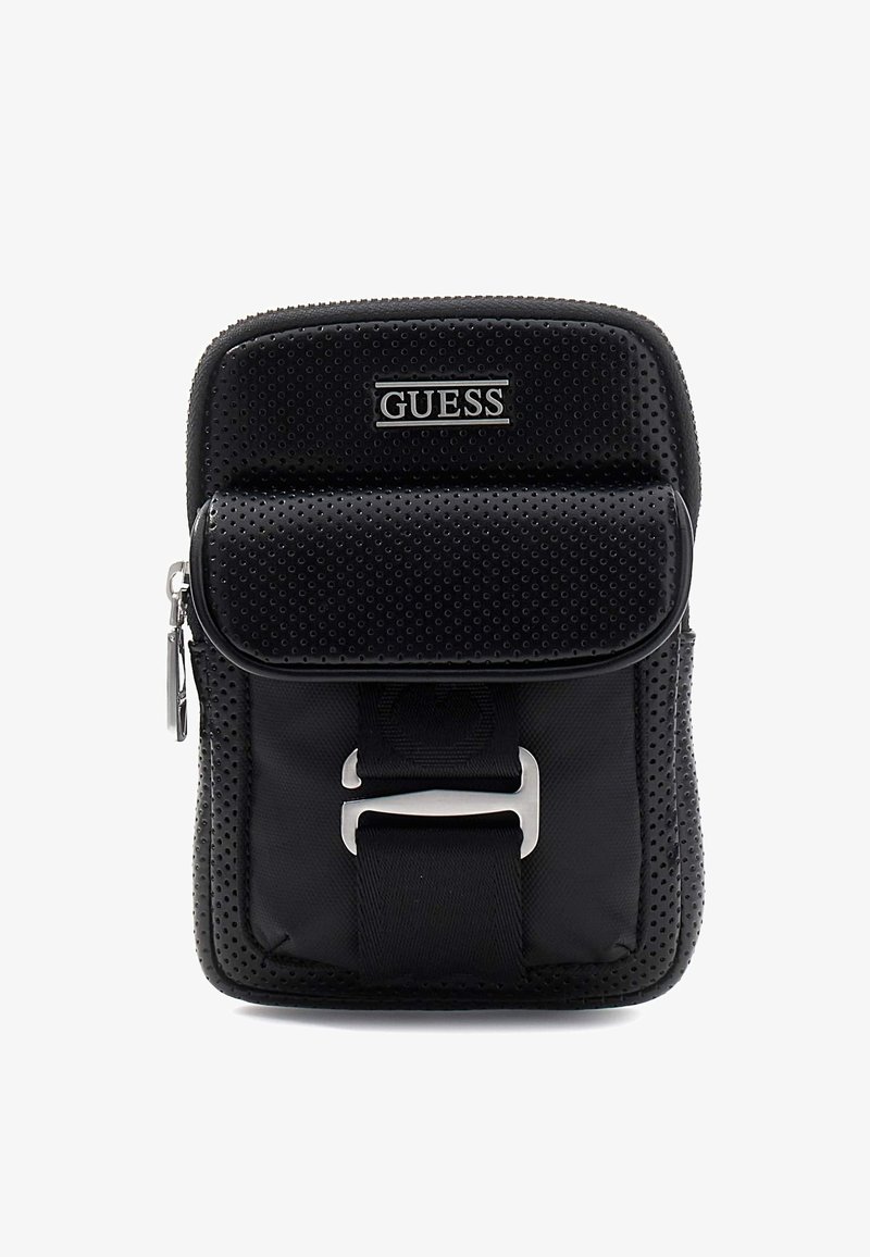 Black perforated GUESS crossbody bag with front flap pocket, silver buckle detail, and zipper closure on top.