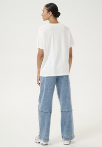 White cotton t-shirt with short sleeves, paired with wide-leg light blue denim jeans, featuring a relaxed fit and clean lines.