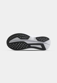 Semelle de basket noire et blanche en caoutchouc texturé, avec des motifs circulaires et ovales, et un intersouffre blanc lisse. Logo de la marque présent.