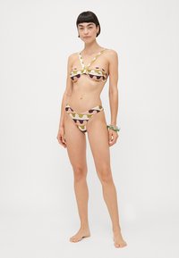 Set di bikini con top a maniche corte e un torsione frontale, caratterizzato da motivi ondulati multicolore in rosa, verde e marrone, abbinato a slip a vita bassa.
