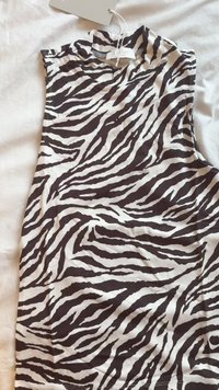 Mouwloos topje met een hoge kraag, met een zwart-wit zebrapatroon. Gemaakt van zachte stof met een gladde textuur.