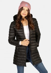 Manteau rembourré noir avec un motif matelassé horizontal, fermeture éclair à l'avant et capuche. Associé à un bonnet en tricot rose clair portant un logo.