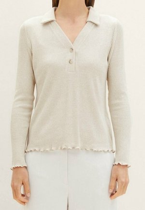 Beżowa prążkowana koszulka polo z długim rękawem, kołnierzykiem, dwoma guzikami oraz falbaną na dole. Gładka tekstura i dopasowany krój.