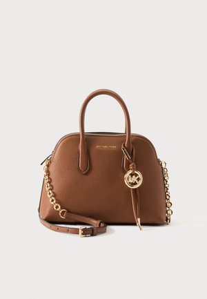 Hnedá kožená kabelka Michael Kors s dvojitými rukoväťami, zlatým reťazovým popruhom a kruhovým príveskom s logom MK na jednoliatom svetlom pozadí.