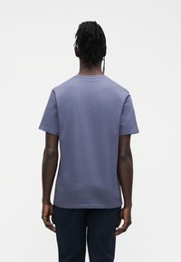 Majica s kratkim rukavima i okruglim izrezom u prigušenoj ljubičastoj boji, s glatkom teksturom, redovitim krojem i jednostavnim dizajnom bez vidljivih logotipa.