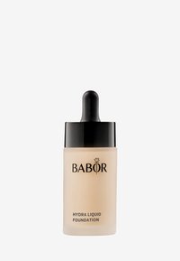 Fond de teint liquide Babor Hydra dans un flacon en verre givré avec un bouchon compte-gouttes noir. L'étiquette présente des lettres blanches sur un fond transparent.