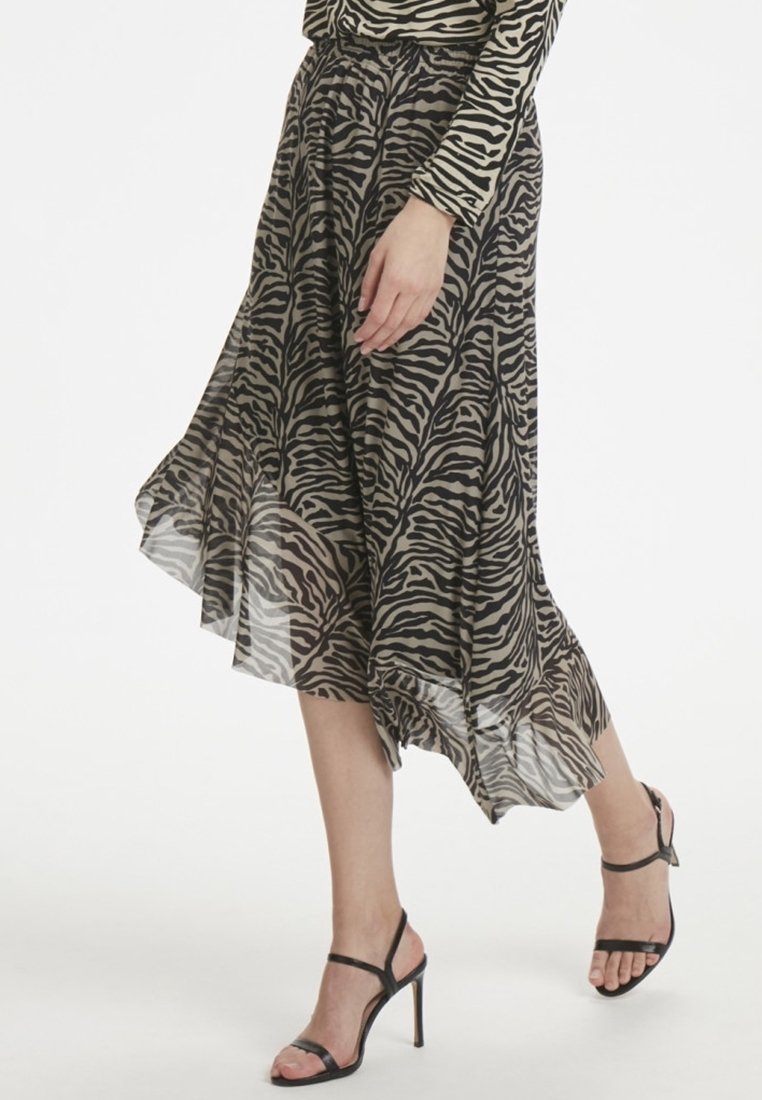 Fließender Midirock aus transparenter Stoff mit einem braun-schwarzen Zebra-Druck, asymmetrischem Saum und kombiniert mit schwarzen Riemchenschuhen.