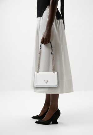 White leather handbag with a structured design, black chain handle, logo accent, and smooth texture, held alongside a white skirt and black heels.