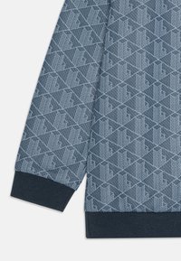 Sudadera azul con patrón que presenta un diseño geométrico en azul más claro, puños acanalados y una tela texturizada.