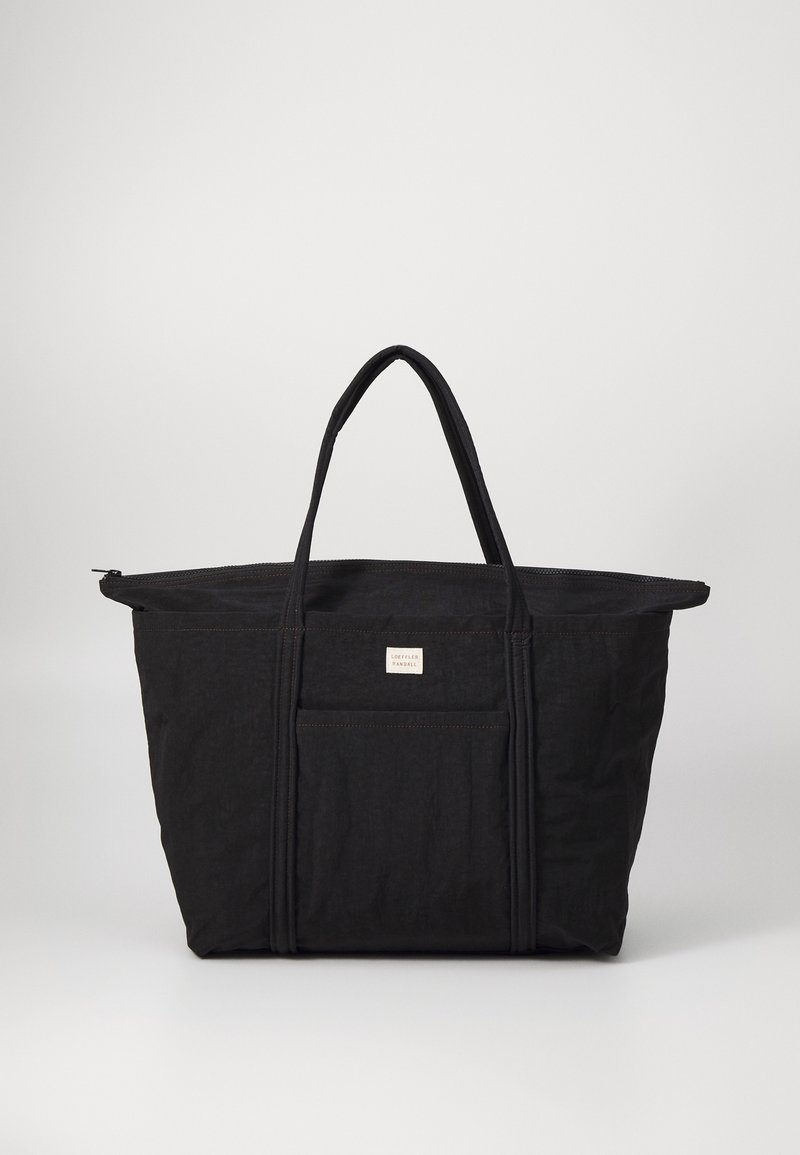 Black tote bag made of durable fabric, featuring two sturdy handles, a zip closure, and a front pocket with a small branded label.
