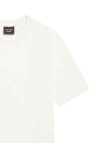 Vit kortärmad t-shirt med en strukturerad mönster och rund halsringning. Har en svart varumärkesetikett bak.