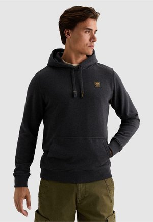 Man wearing dark gray hooded sweatshirt with front pocket and olive green cargo pants, looking to the side against a plain background.