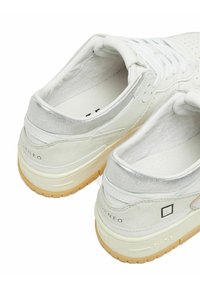Sneaker bianchi in pelle con un accento metallico argento sul tallone, design perforato e suola in gomma. Presentano il marchio sul tallone.
