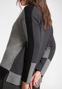 Grau-schwarzer, farbblockierter Strickpullover mit gerippten Bündchen und Saum, mit lockerem Sitz und weicher Wollstruktur.