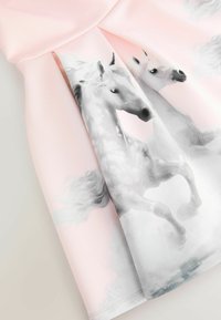 Vaaleanpunainen mekko, jossa on painettu kuvio kahdesta valkoisesta yksisarvisesta, joilla on suihkuavat harjat pehmeää, pilvistä taustatekstuuria vasten.