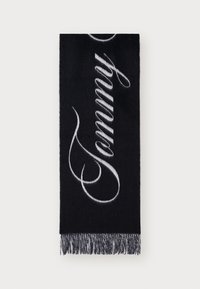 Écharpe noire avec le texte "Tommy" en cursive blanc. Possède des bords frangés, fabriquée en matériau doux avec une texture lisse.