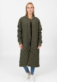Pikowana długa kurtka w oliwkowym kolorze, z zamkiem z przodu, prążkowanymi mankietami oraz boczną kieszenią zapinaną na zamek. Gładki materiał i lekka konstrukcja.
