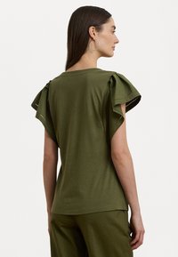 T-shirt verde oliva con maniche corte arricciate e cuciture decorative lungo i bordi. Tessuto morbido, vestibilità comoda.