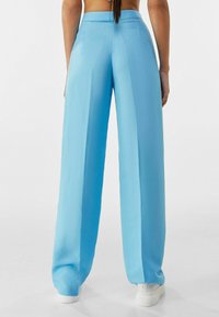 Light blue wide-leg pants, featuring a smooth texture, high waist, and straight cut, shown from the back with minimal detailing.