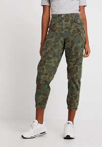 Camouflage cargo broek in groen en bruin, met een relaxte pasvorm, elastische enkels, zijzakken en een knoopsluiting.