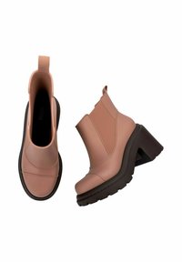 Różowe botki za kostkę z grubiutkim brązowym obcasem, wykonane z gładkiego materiału, z elastycznymi panelami po bokach i pętelką ułatwiającą zakładanie.