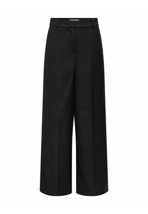 Melnas platām kājām bikses ar gludu priekšpusi, sānu kabatām un vienmērīgu auduma tekstūru. Raksturīga piegrieztā jostas vieta un tīras līnijas.