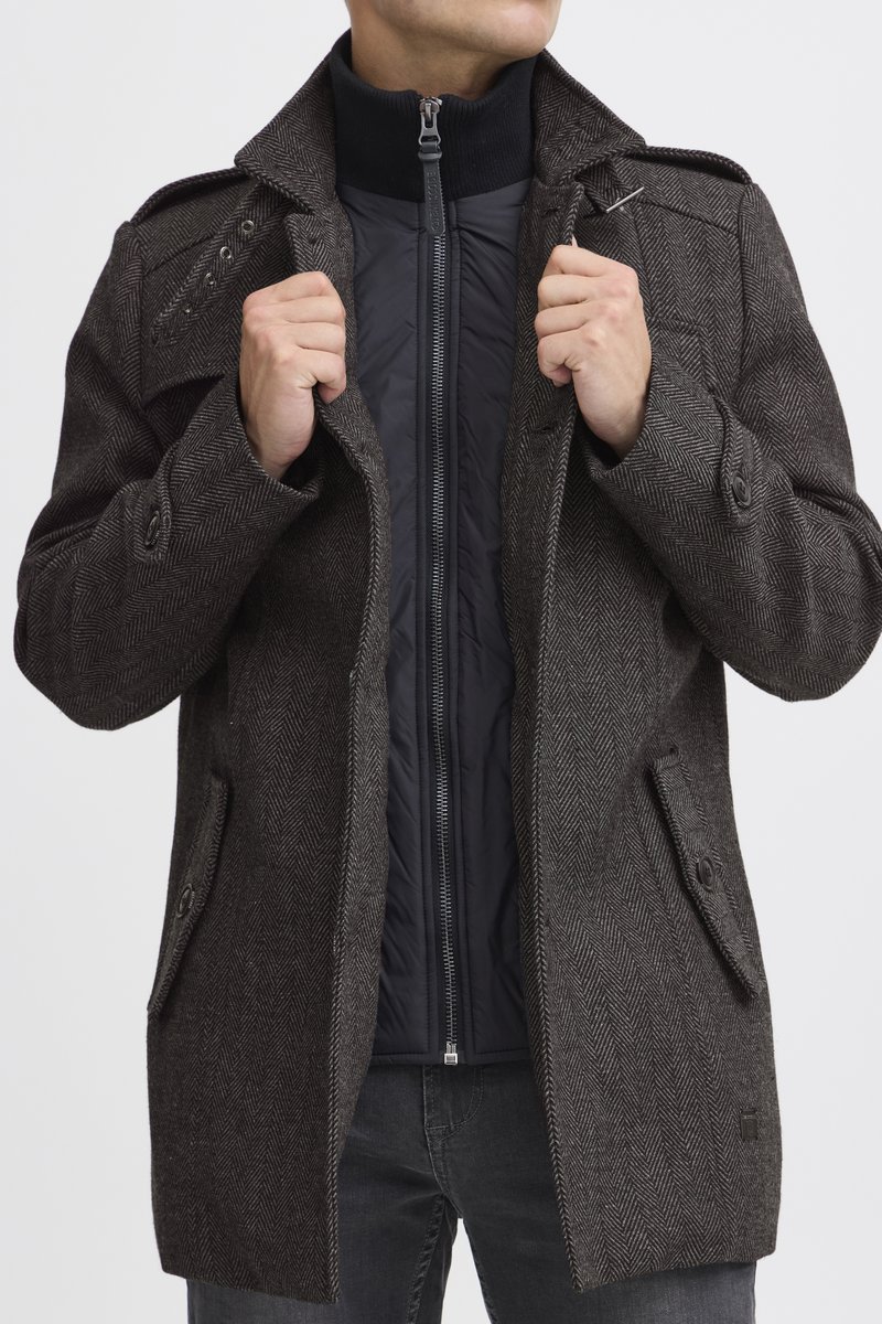 Brown herringbone coat with a black zippered inner liner. Features a wide collar, buttoned pockets, and a streamlined fit.