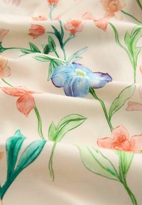 Tissu léger avec un motif floral comprenant des fleurs bleues, corail et pêche, ainsi que des feuilles vertes sur de fines tiges.