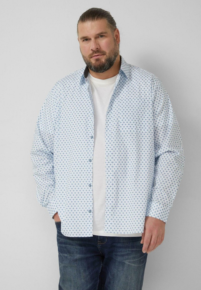 Hellblaues Hemd mit Rautenmuster, durchgeknöpfter Vorderseite und langen Ärmeln, getragen über einem weißen T-Shirt und kombiniert mit dunklen Jeans.