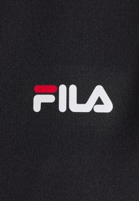 Tissu noir texturé avec le logo de la marque FILA en lettres blanches et rouges centrées.