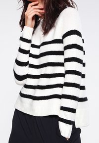 Sweter w czarno-białe paski z miękkiego dzianinowego materiału. Posiada okrągły dekolt, długie rękawy oraz ściągacz u dołu. Casualowy, luźny krój.